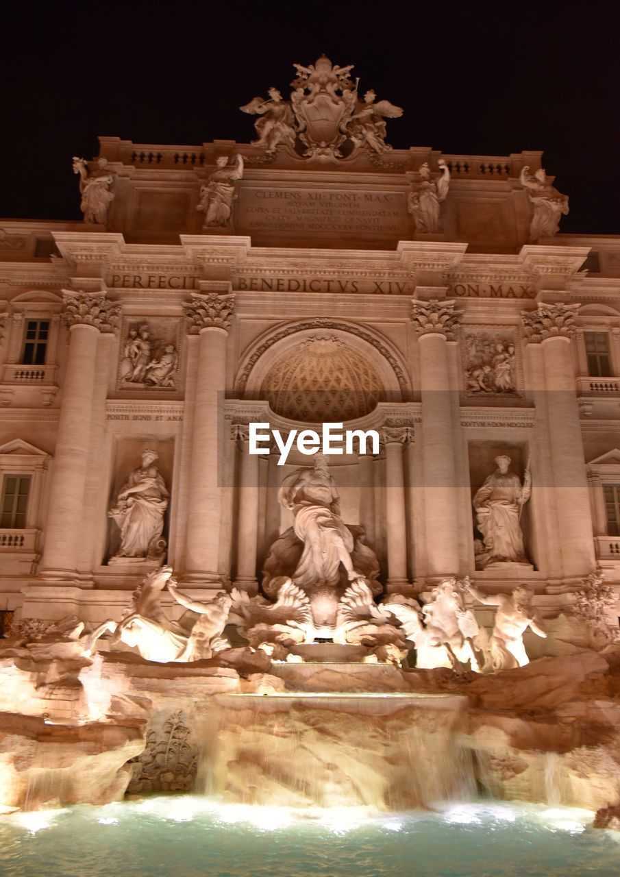 LOW ANGLE VIEW OF STATUE AGAINST ILLUMINATED BUILDINGS