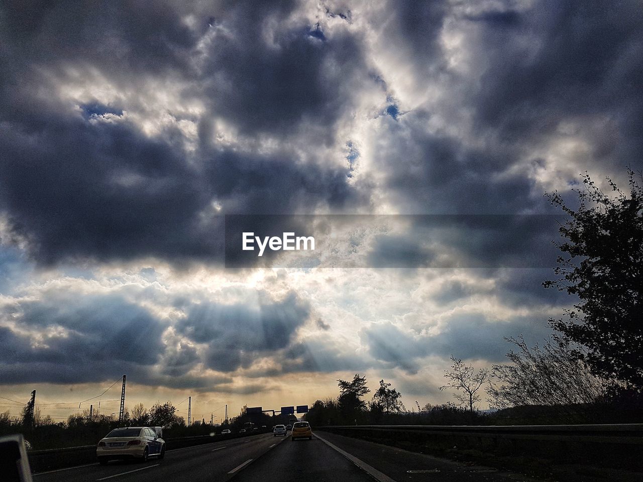 CARS ON ROAD AGAINST STORM CLOUDS