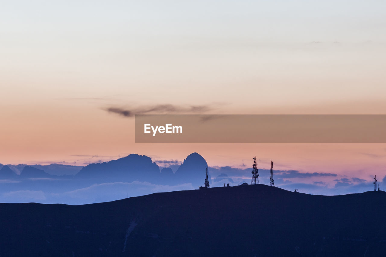 Tv antennas with dolomitic background silhouette from monte pizzoc summit, veneto, italy