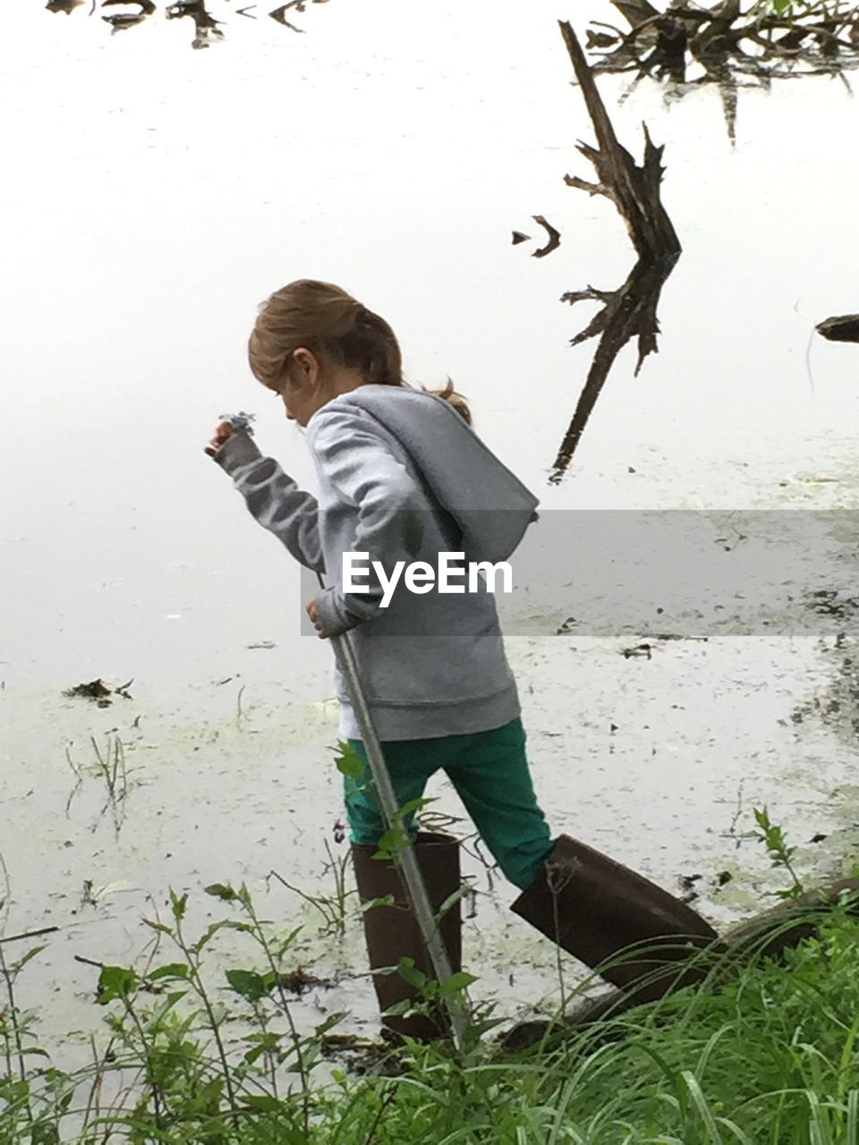 Girl walking on grass against lake