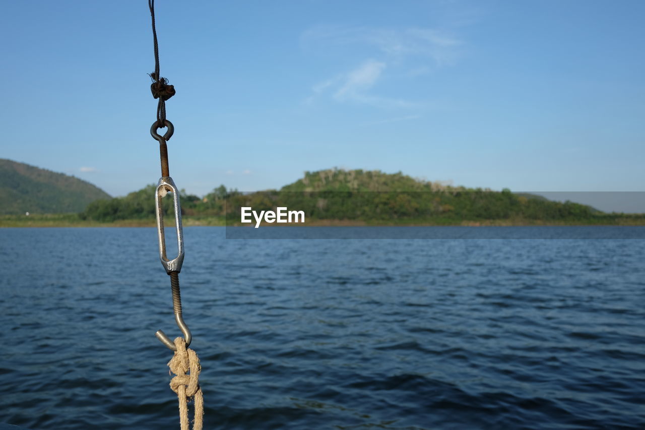 CLOSE-UP OF ROPE HANGING ON RIVERBANK