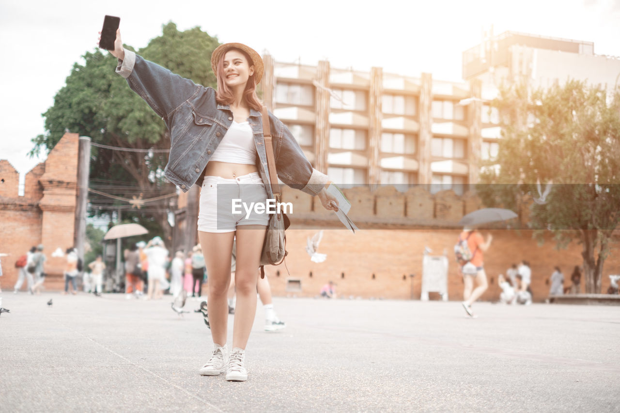 Full length of young woman standing on street in city