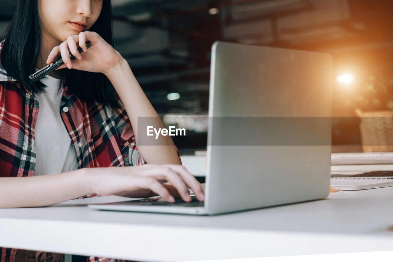 Midsection of woman using laptop on table