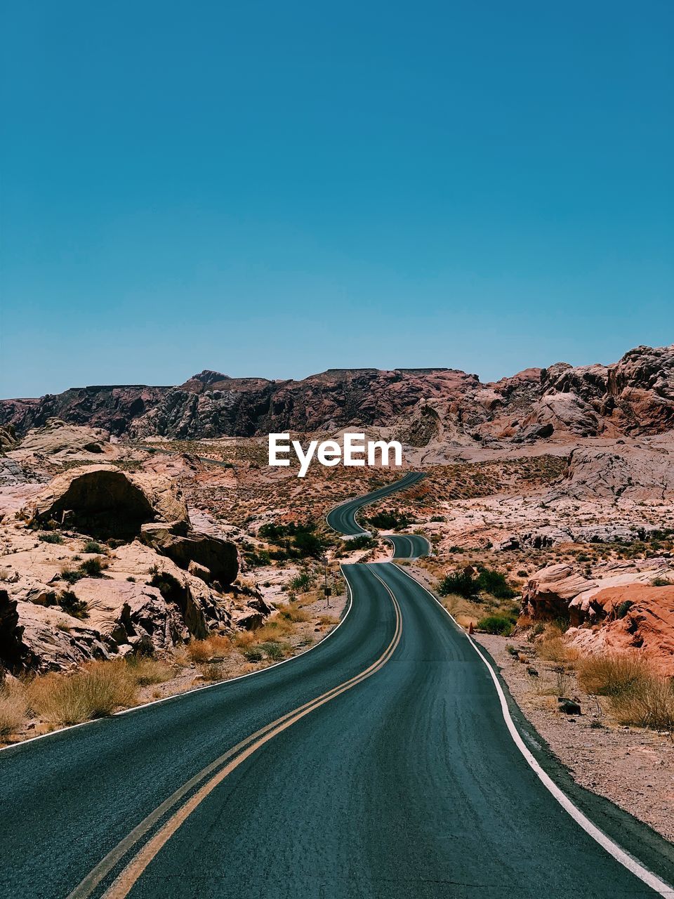 Road amidst landscape against clear blue sky