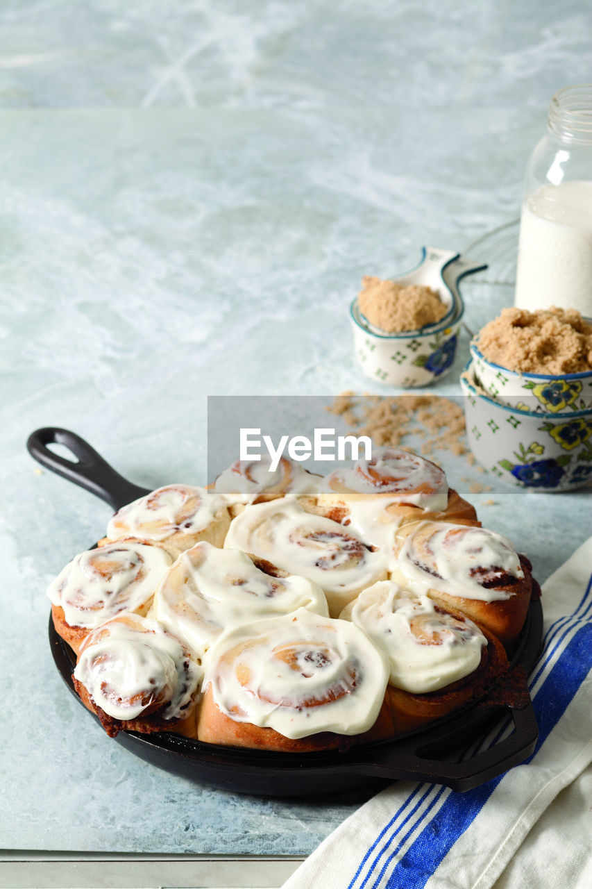 Close-up of cream on cinnamon buns in cooking pan at home