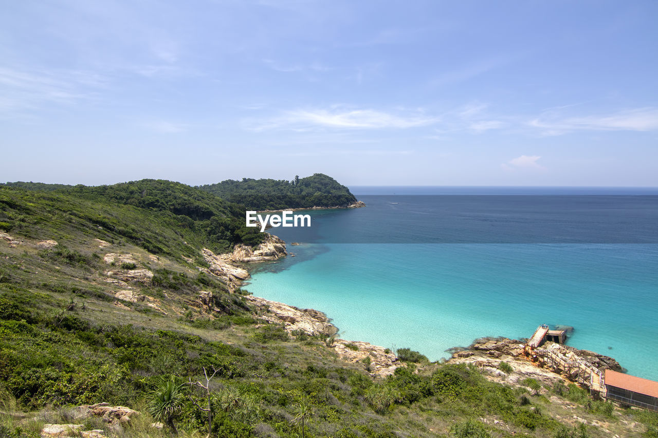 Scenic view of sea and mountains against cloudy sky on sunny day