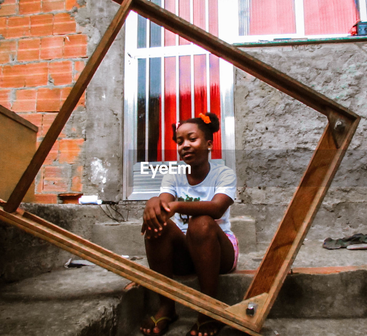 PORTRAIT OF SMILING YOUNG MAN SITTING ON BUILDING