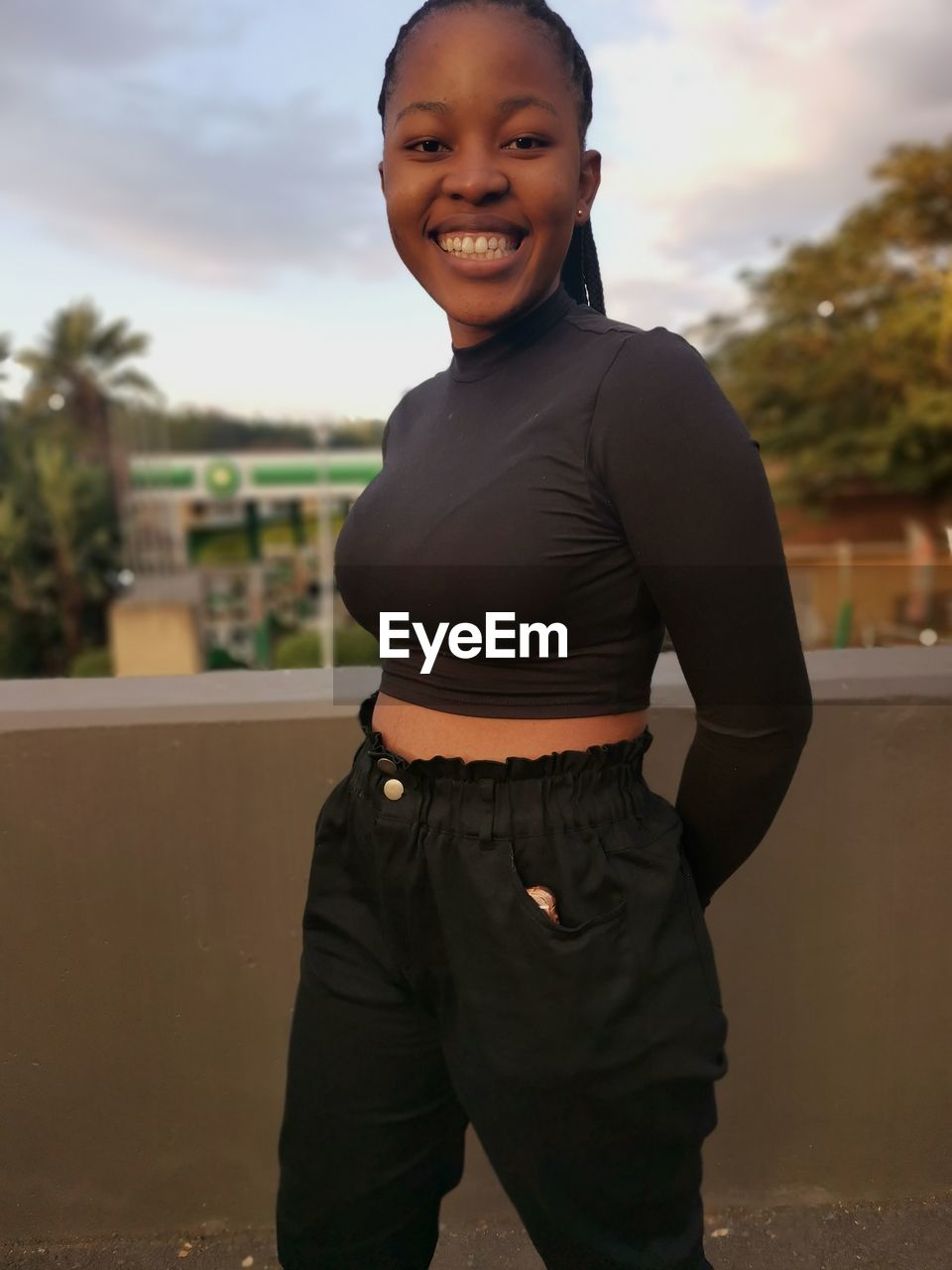 PORTRAIT OF HAPPY GIRL STANDING AGAINST SKY