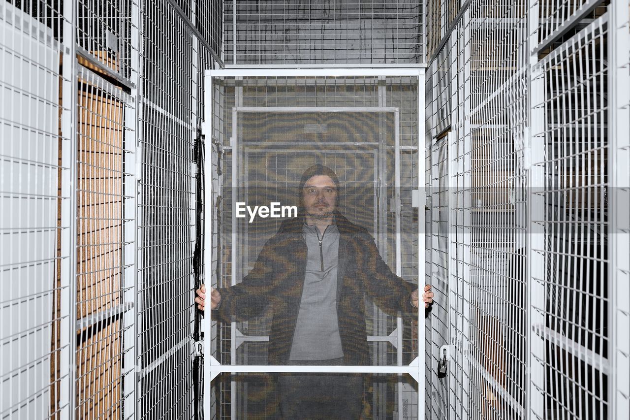 Portrait of man standing by fence in underground