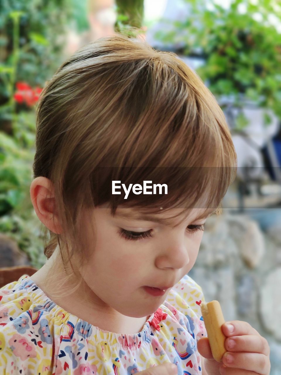 CLOSE-UP PORTRAIT OF CUTE GIRL LOOKING AT ICE CREAM