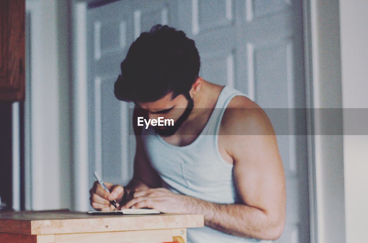 Close-up of man writing in book at table