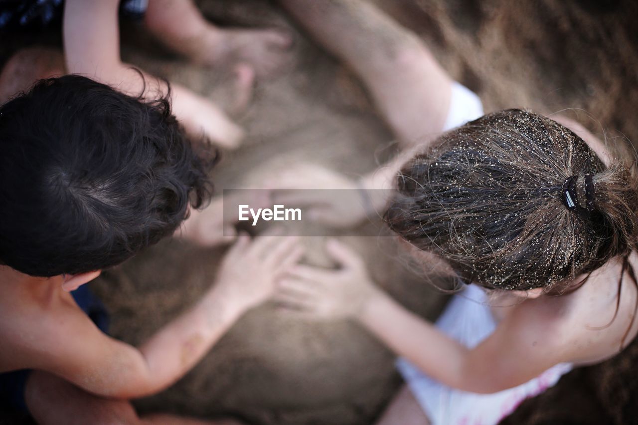 Directly above shot of friends playing with sand at beach