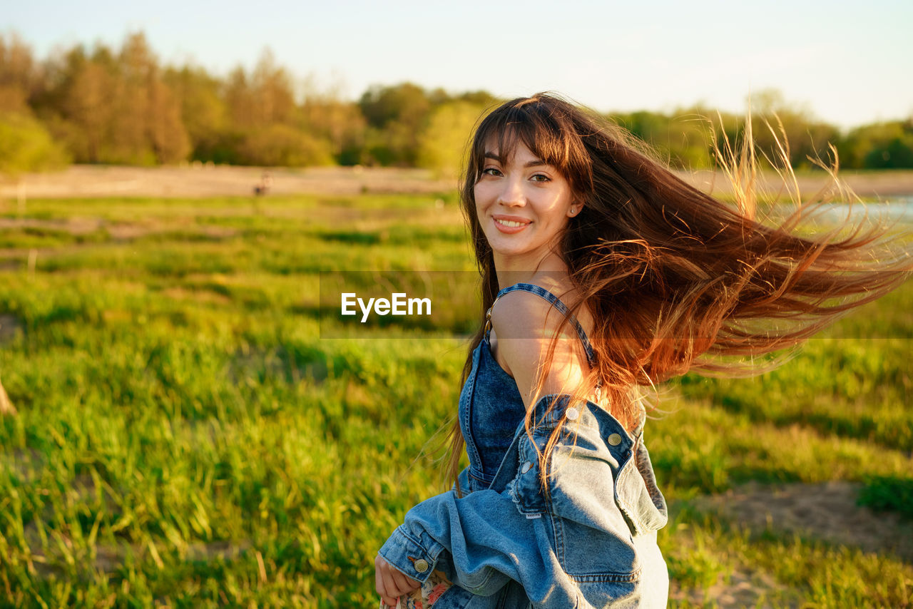 Portrait of a beautiful young woman with fluttering hair in nature