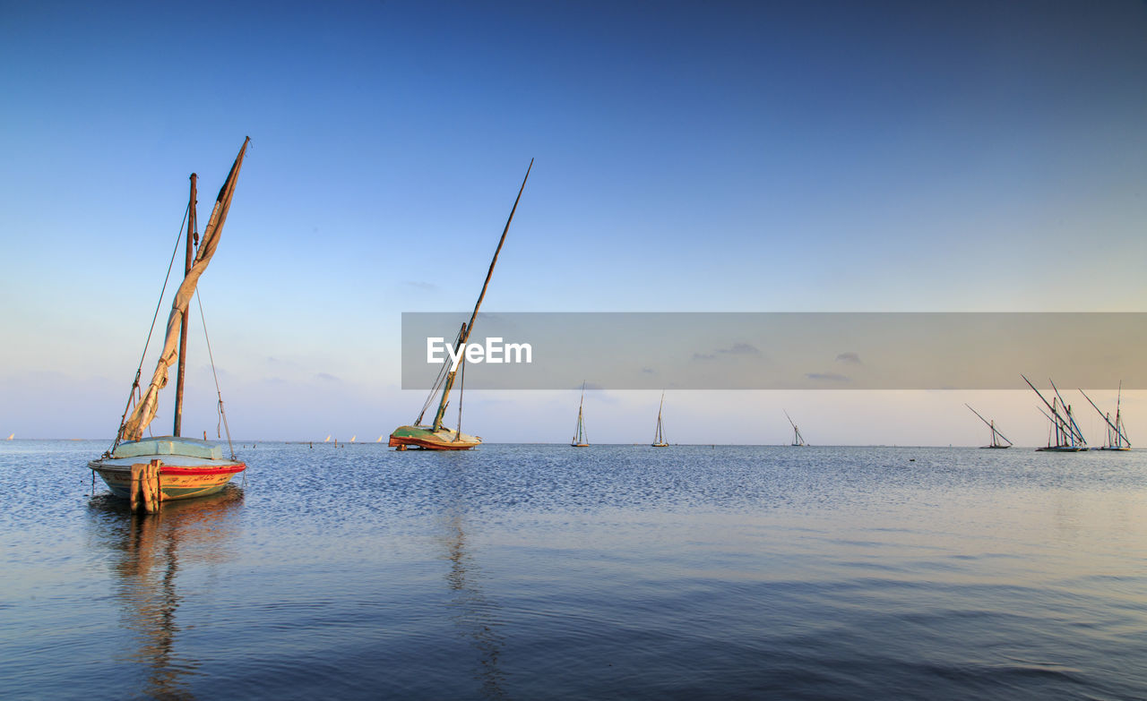 Boats moored on sea at sunset