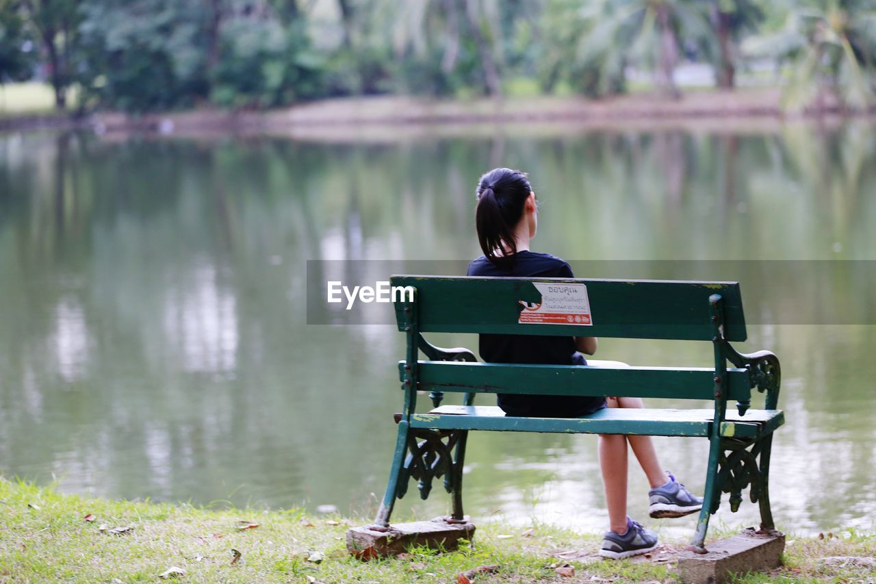 Girl sitting on bench at lakeshore