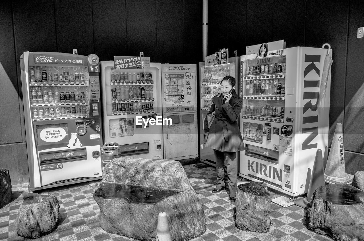 MAN STANDING ON ILLUMINATED STORE