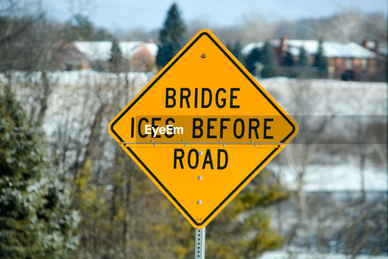 Close-up of yellow road sign in city during winter