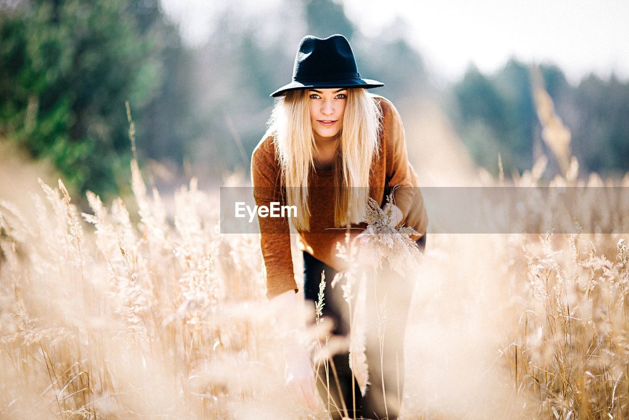 PORTRAIT OF YOUNG WOMAN STANDING ON GROUND