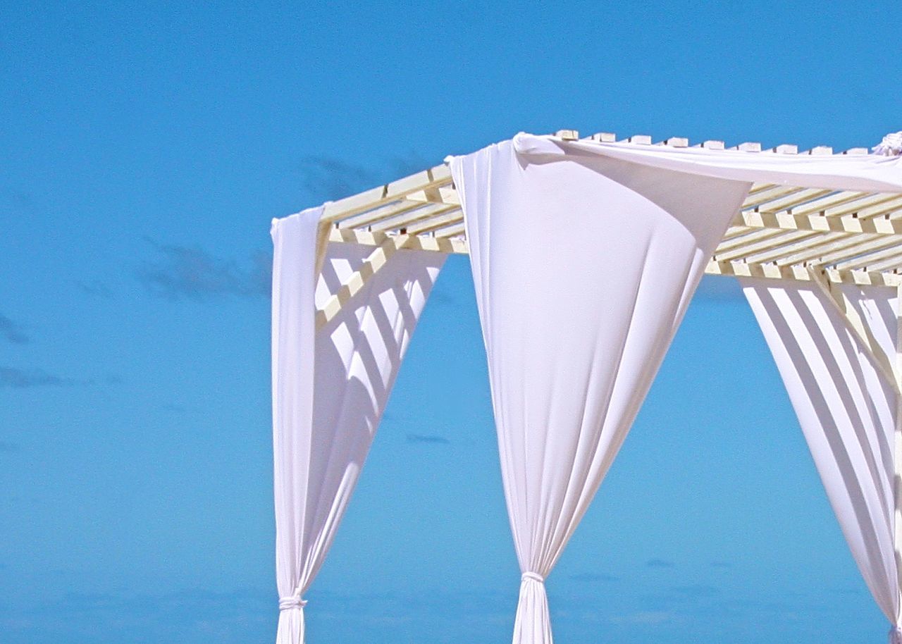 Low angle view of curtain on structure against blue sky