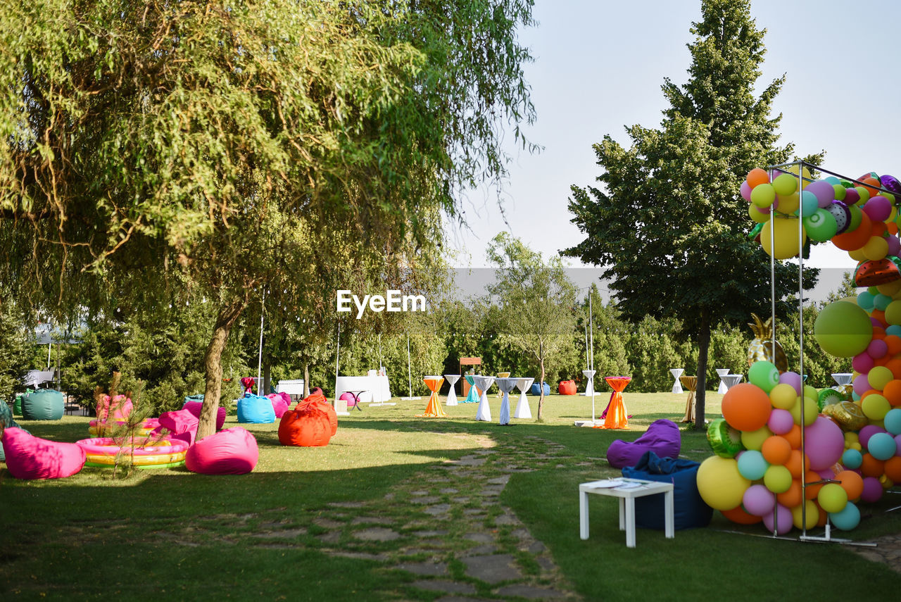 MULTI COLORED BALLOONS IN PARK AGAINST SKY