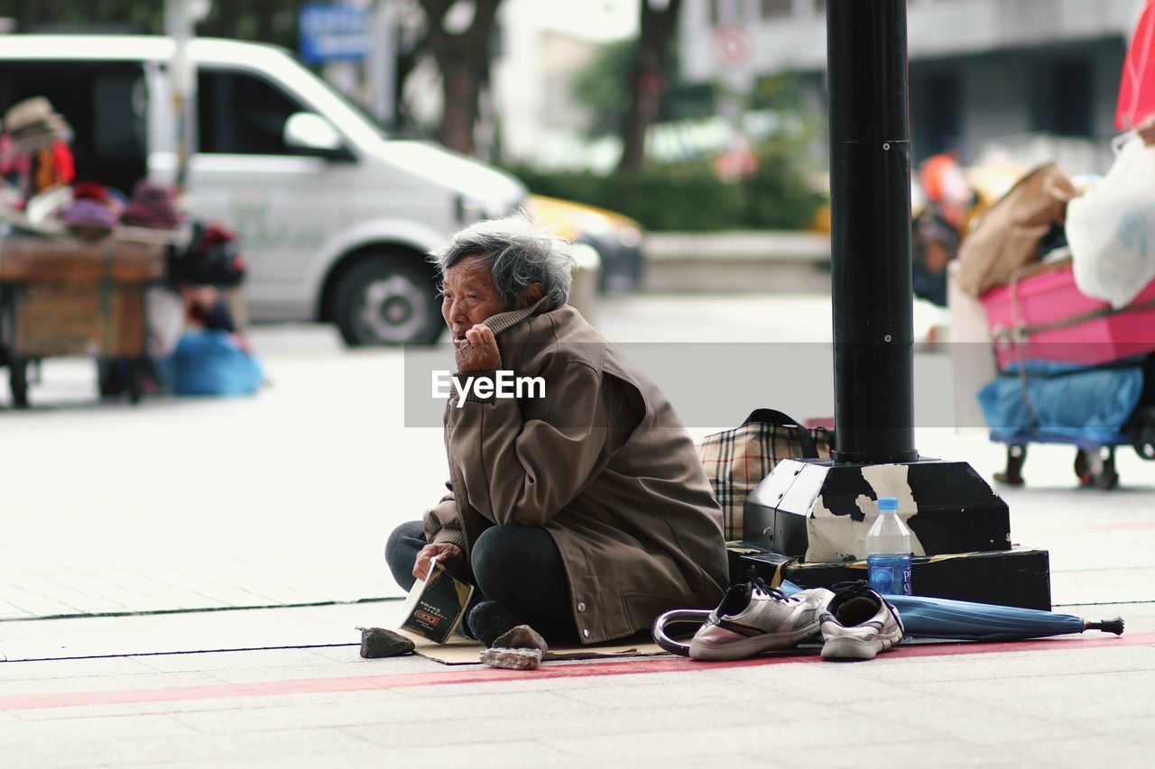 PEOPLE SITTING ON STREET AGAINST CITY