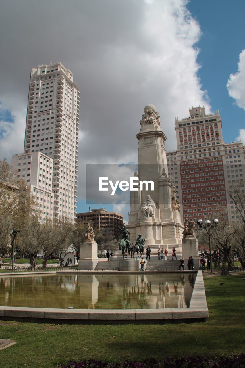 Cervantes monument and buildings at plaza de espana against cloudy sky