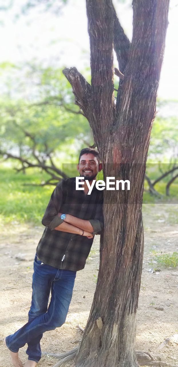 PORTRAIT OF MAN BY TREE TRUNK