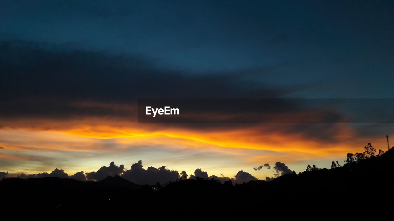 SCENIC VIEW OF SILHOUETTE MOUNTAINS AGAINST ORANGE SKY