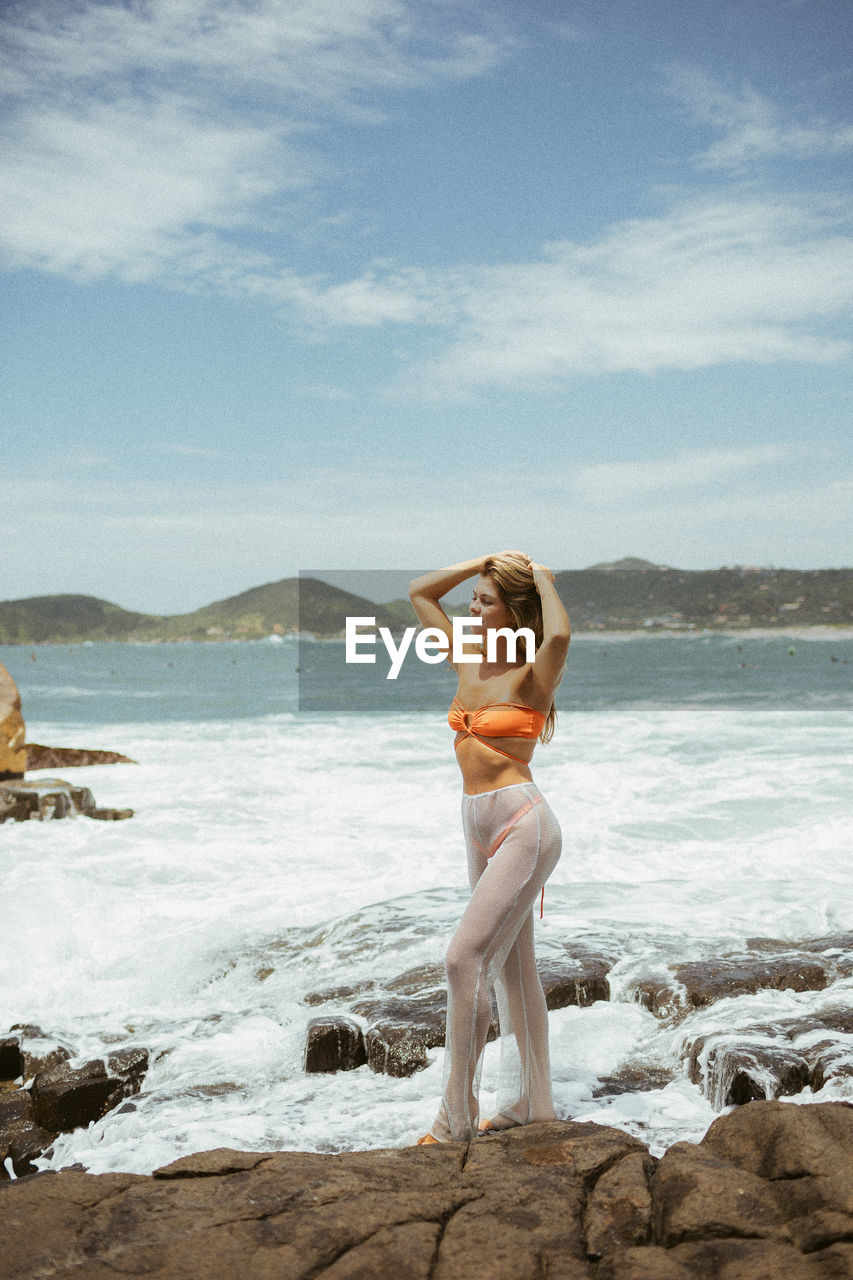 Full length of woman standing at beach against sky