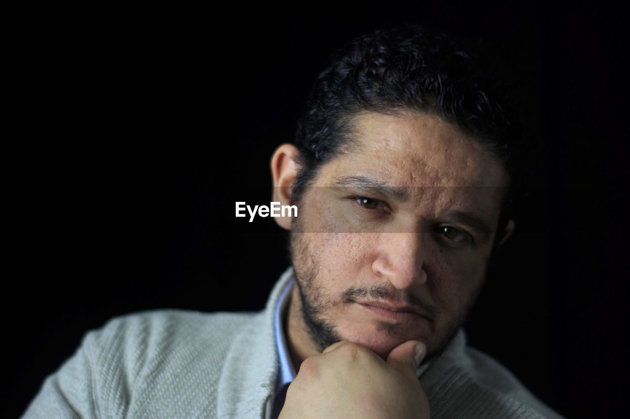 Close-up portrait of man against black background