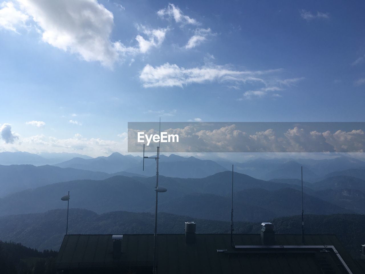 Antenna on rooftop of house against mountain range