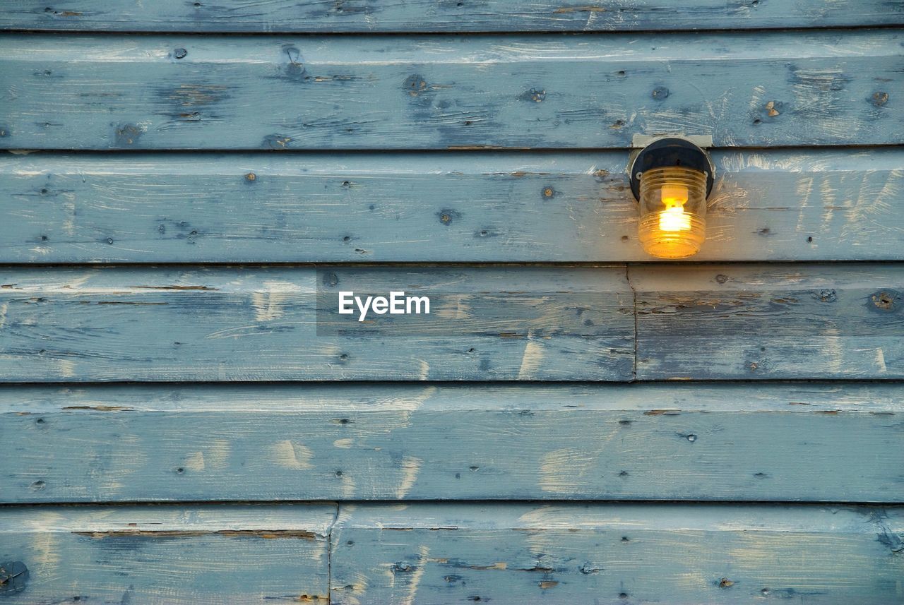 Close-up of illuminated lighting equipment on wooden wall