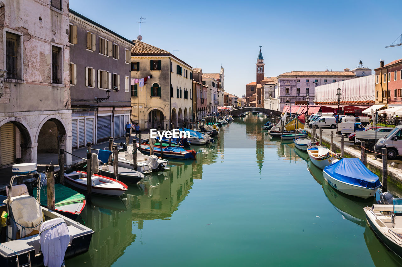 Boats moored in canal amidst buildings against sky