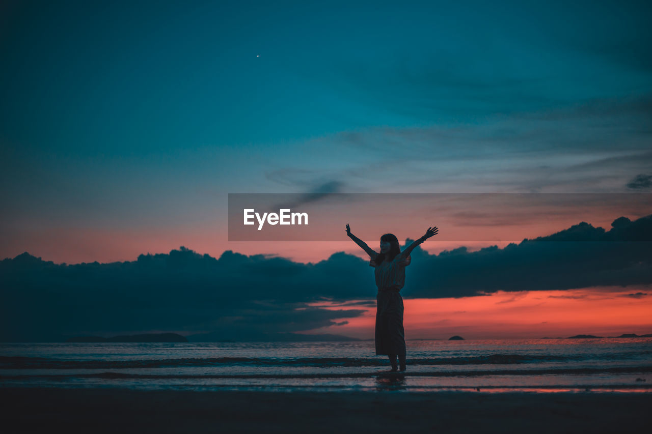 SILHOUETTE MAN STANDING BY SEA AGAINST SKY AT SUNSET