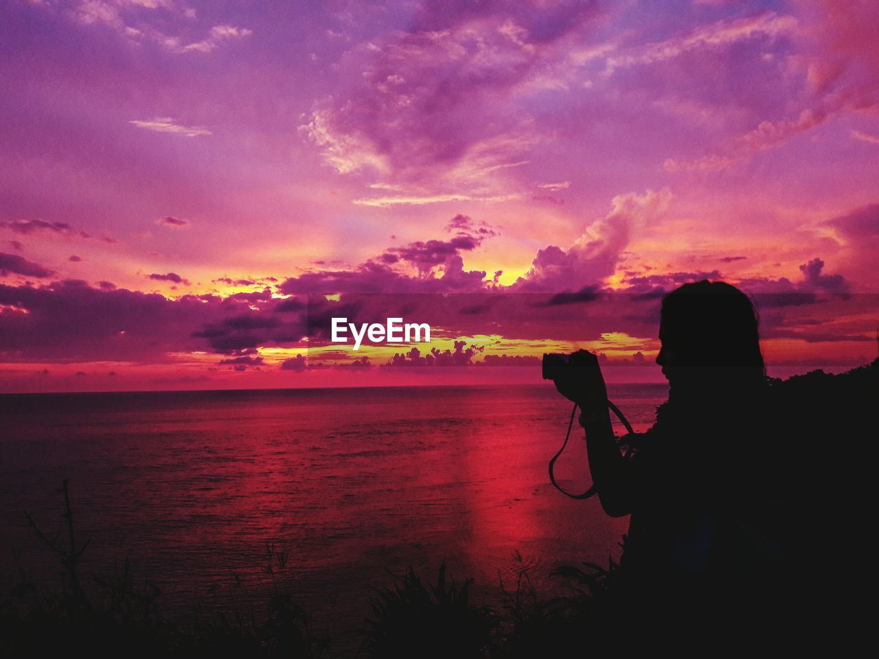 SILHOUETTE WOMAN PHOTOGRAPHING AT SUNSET