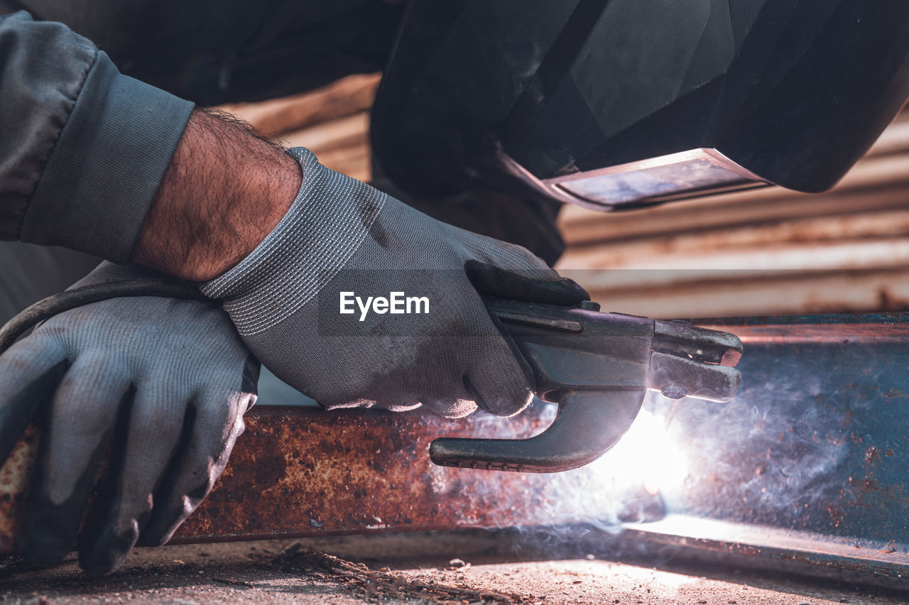 CLOSE-UP OF MAN WORKING ON METAL GRILL