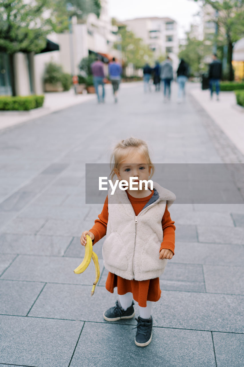 portrait of cute girl standing on footpath