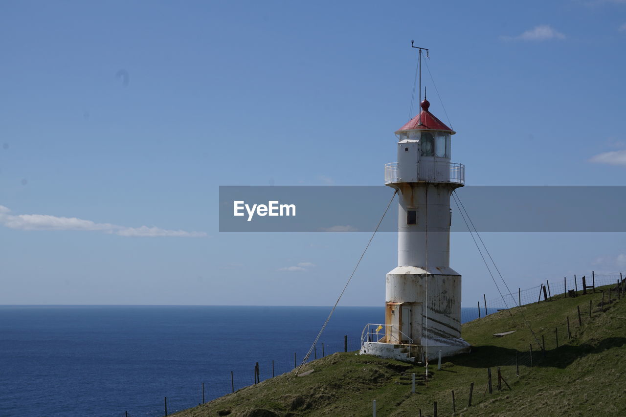 Lighthouse by sea against sky