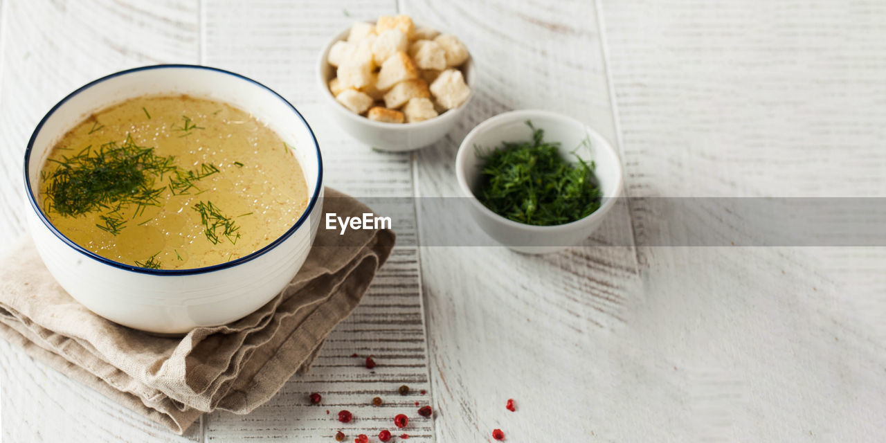 Healthy bone broth in a bowl with dill on a light wooden background. copy space