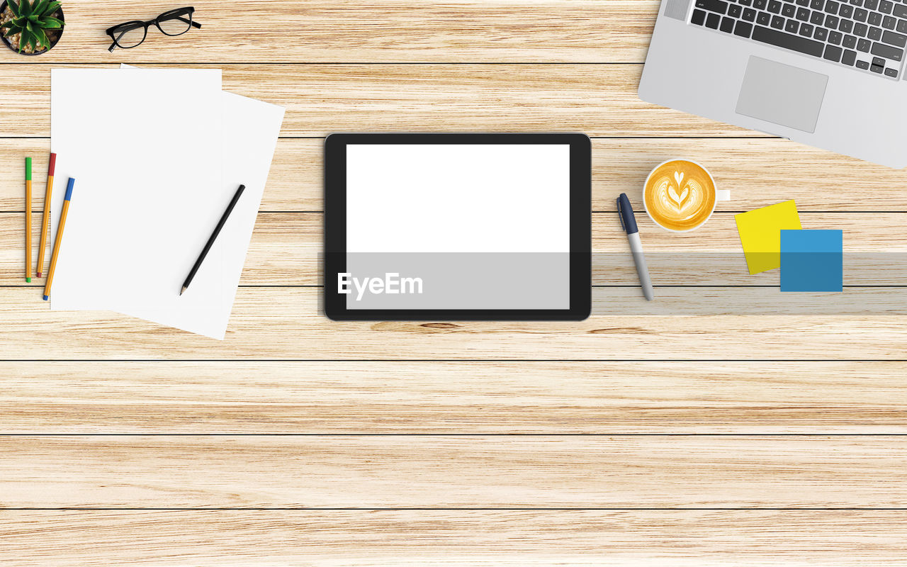 High angle view of technology with coffee and office supplies on wooden table