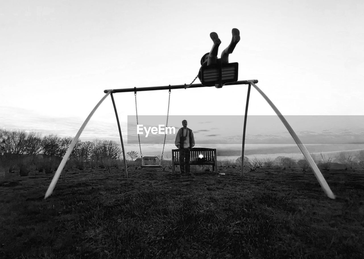 View of silhouette people on swings against sky