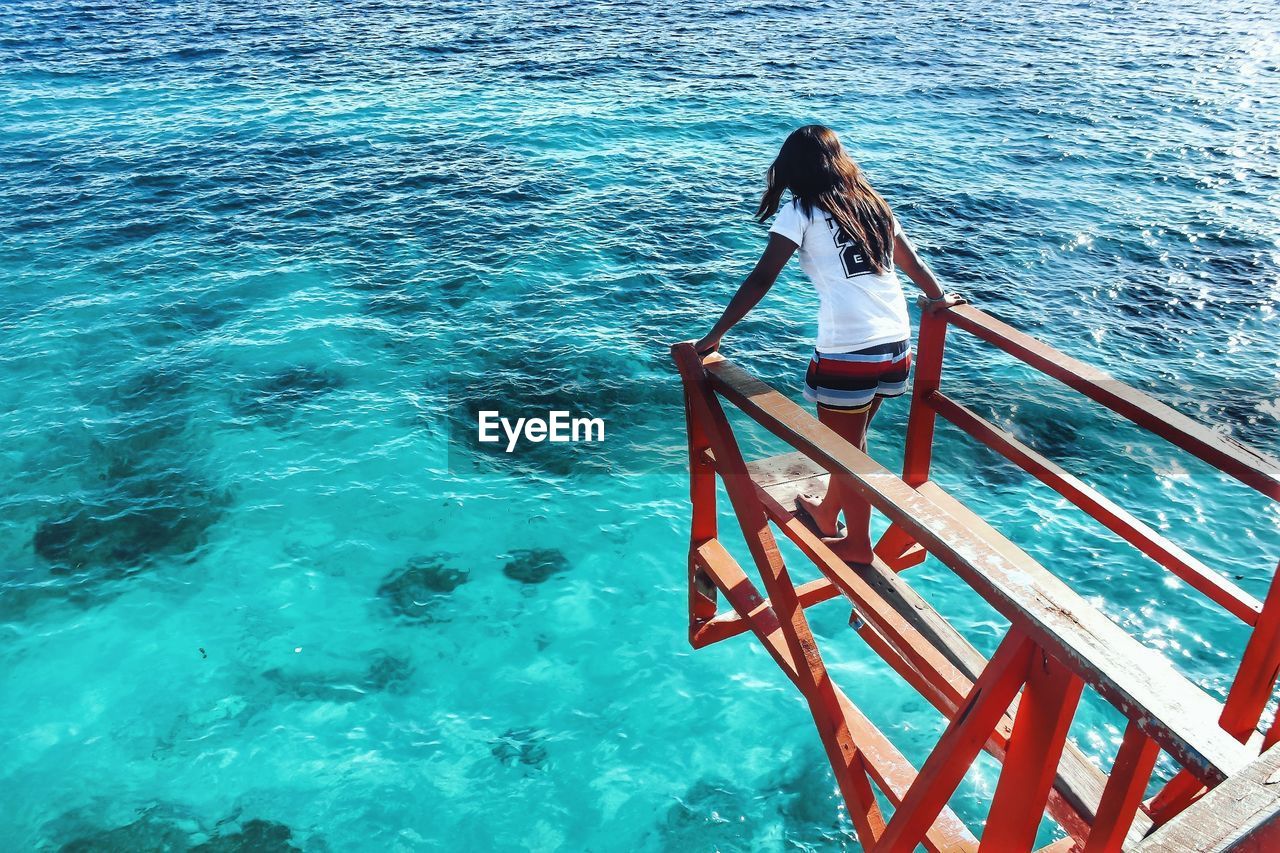 High angle view of woman standing on diving platform over sea