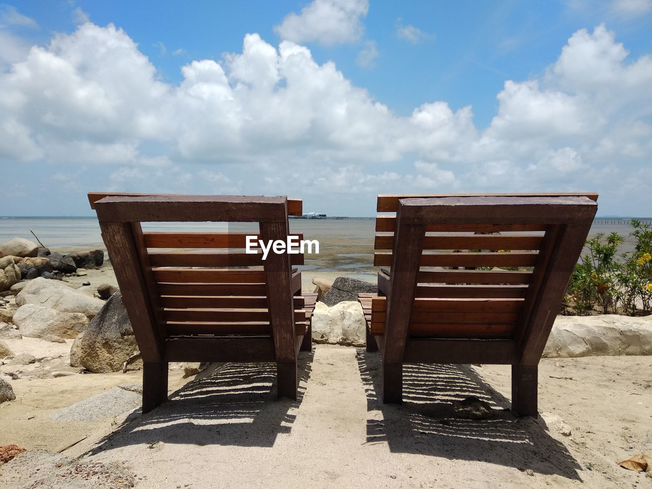 DECK CHAIRS ON BEACH AGAINST SKY