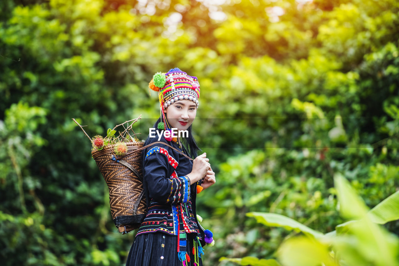 Portrait of smiling woman wearing traditional clothing standing against trees in forest