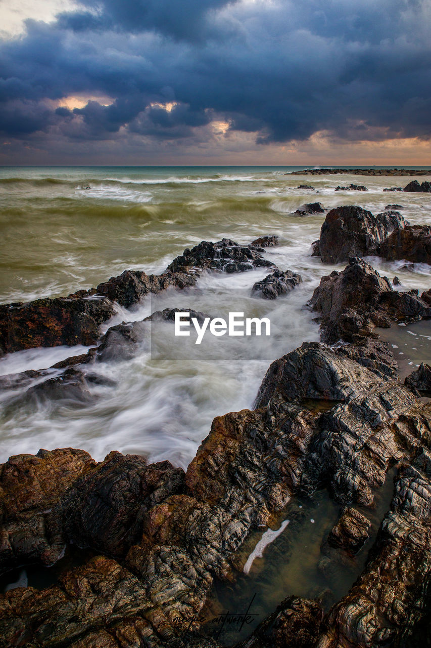 SCENIC VIEW OF ROCKS ON SHORE AGAINST SKY