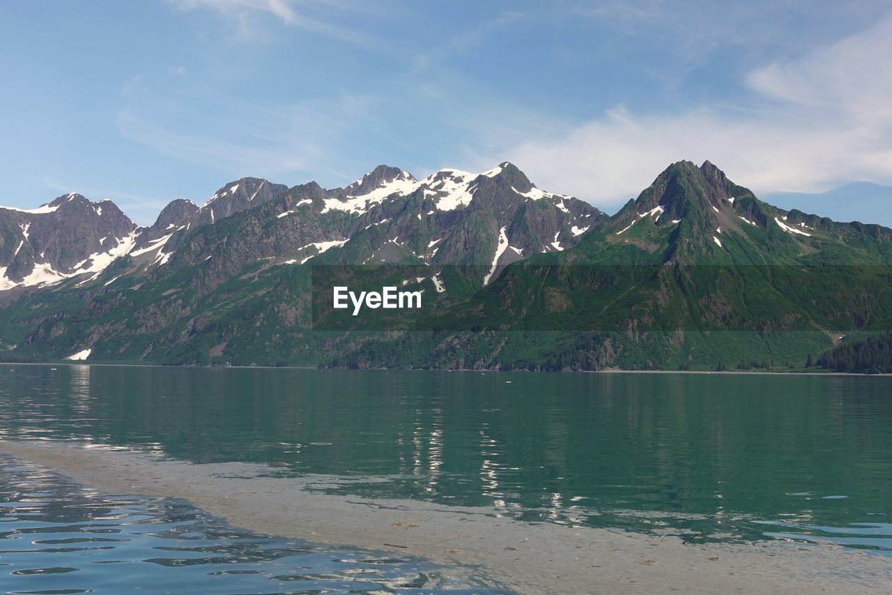 Scenic view of lake by mountains against sky