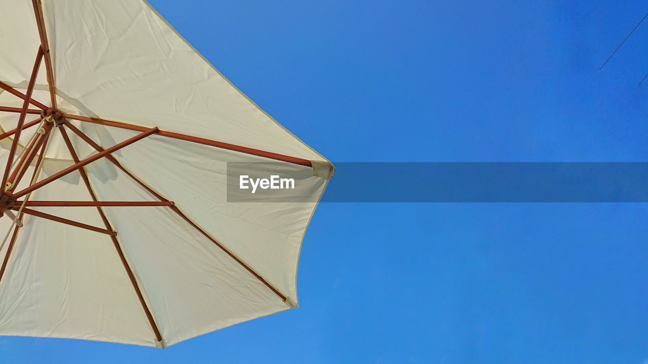 Low angle view of umbrella against clear blue sky