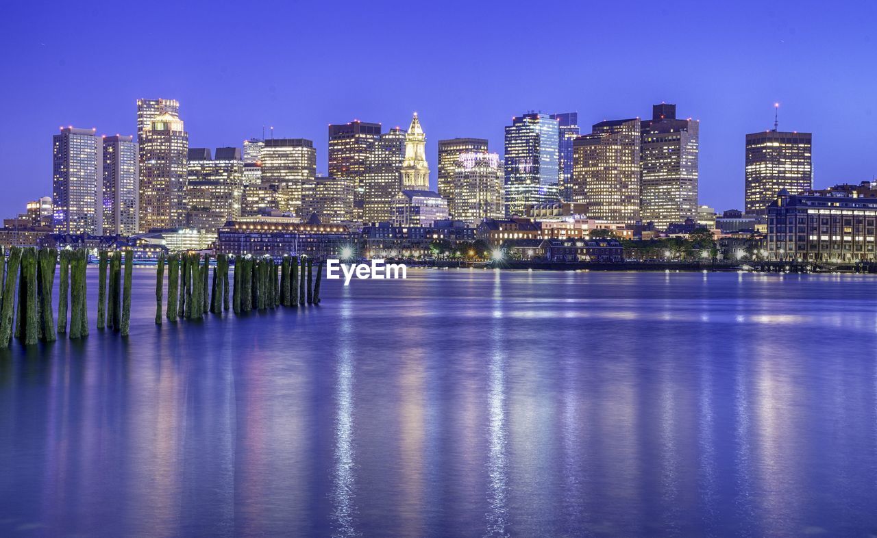 Illuminated buildings in city against clear sky