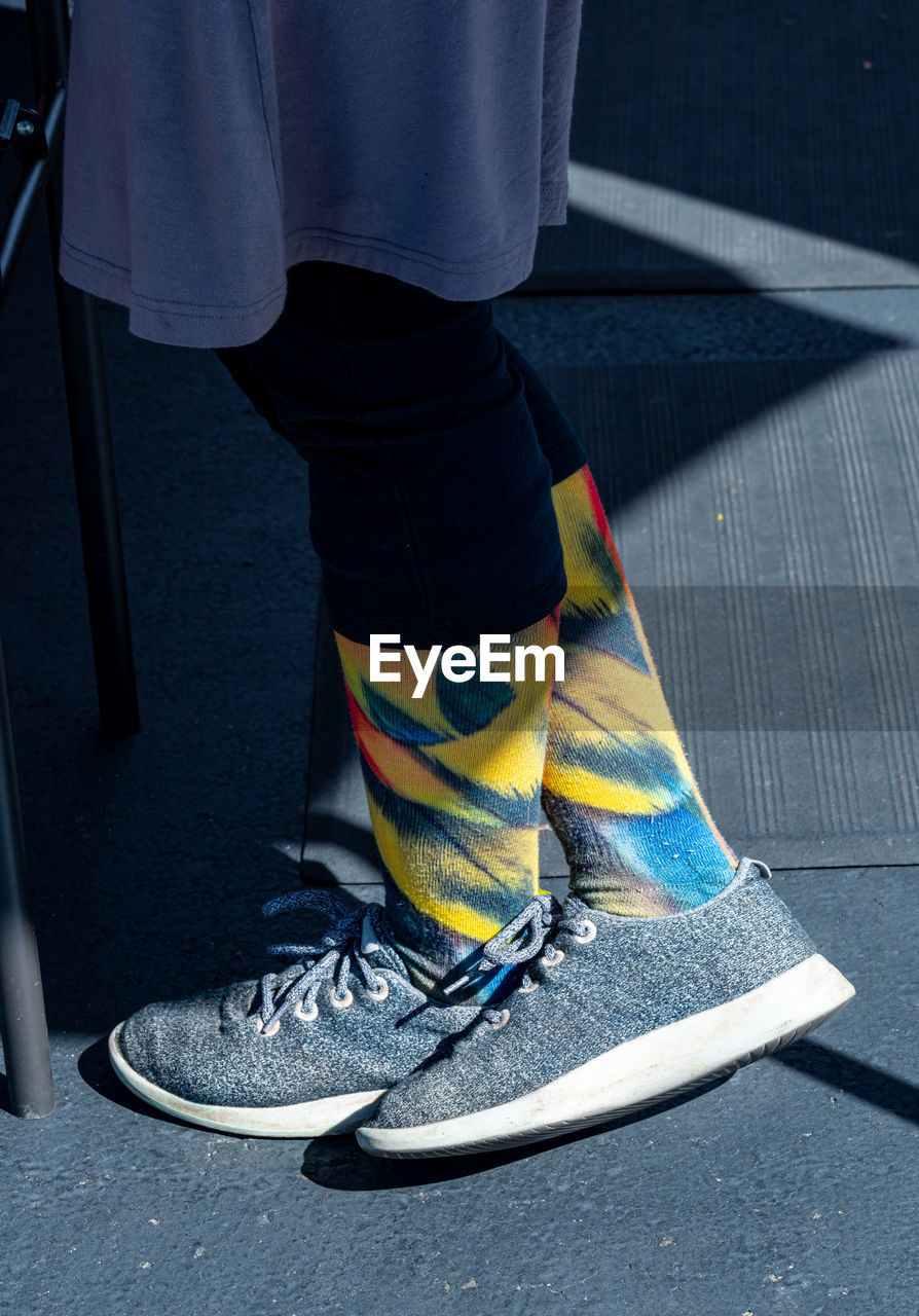 Colorful patterned socks on woman wearing grey tennis shoes and dress