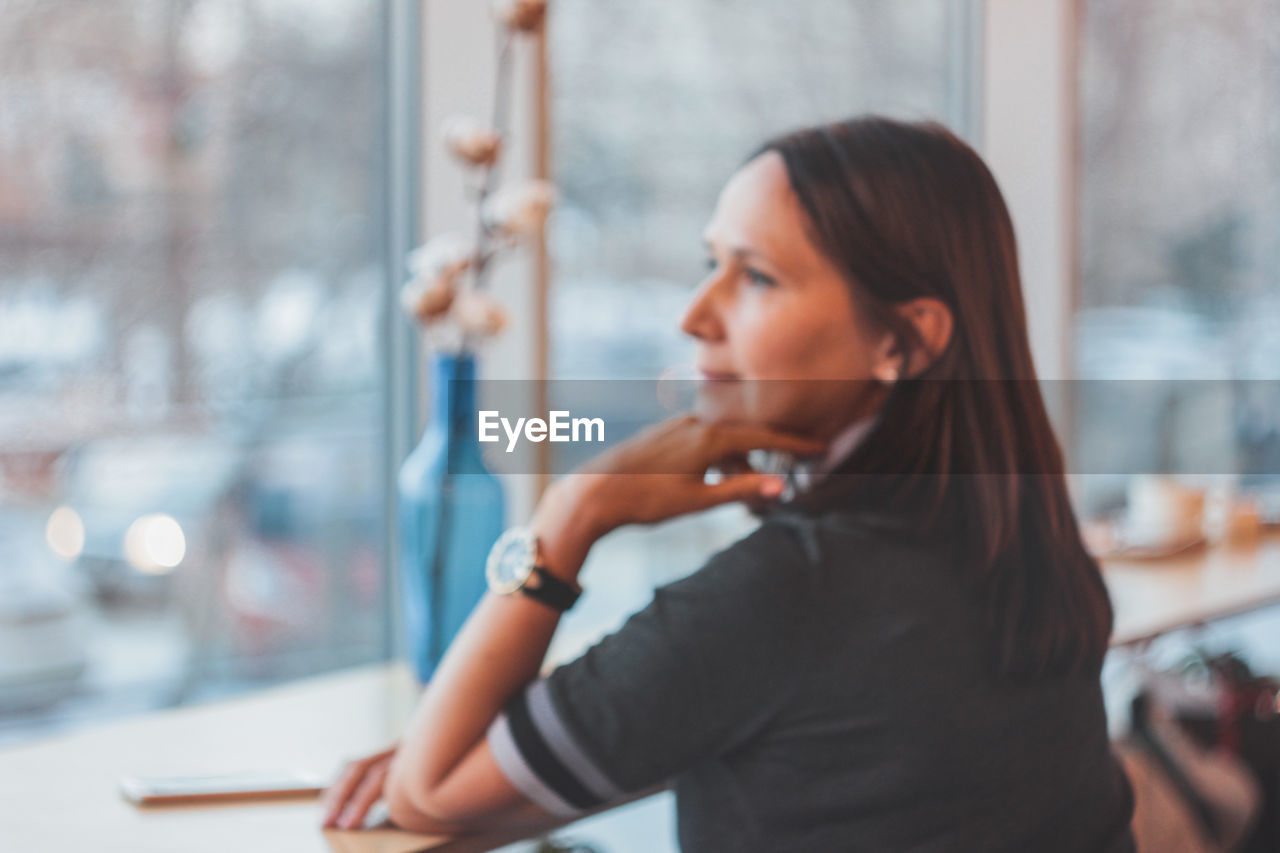 Woman looking through window at cofee shop